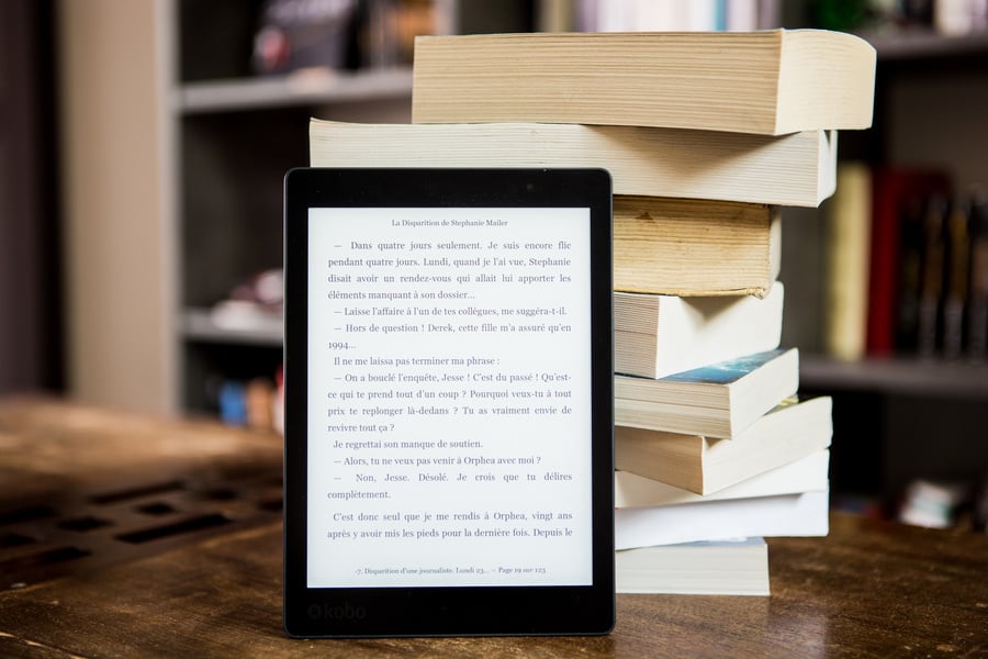 A kindle and a stack of books